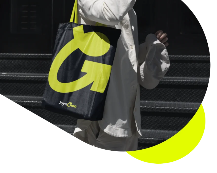 A shopper carrying a Joyagoo tote bag with a large lime G logo